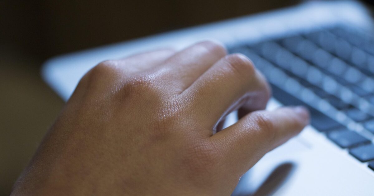 ノートパソコンのキーボードを操作する手のクローズアップ