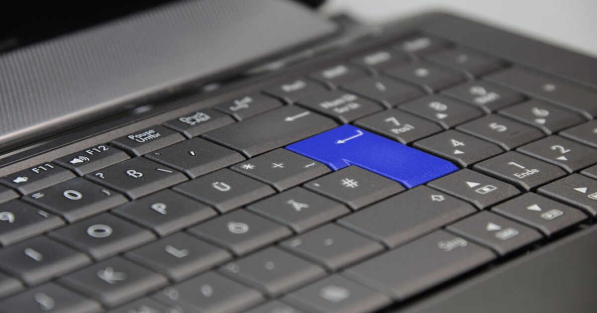 エンターキーが青いノートパソコンのキーボードクローズアップ