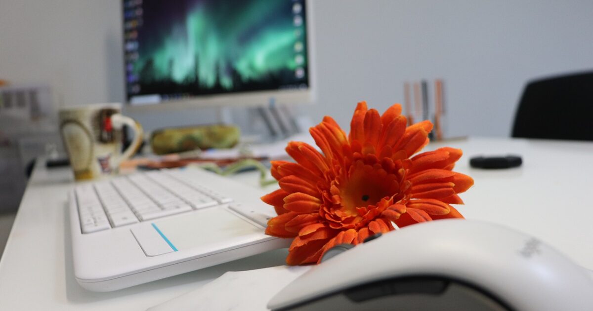 オレンジの花とパソコンが置かれたデスクのクローズアップ