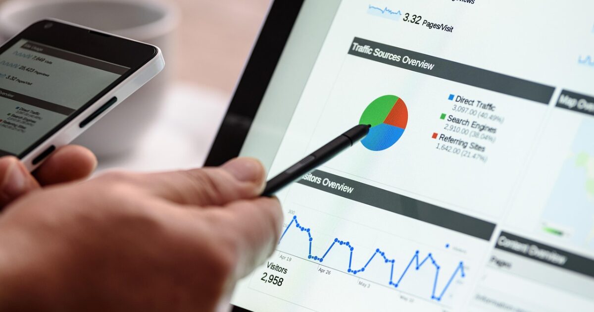 タブレットに表示されたデータ分析画面を指し示す手とスマートフォン