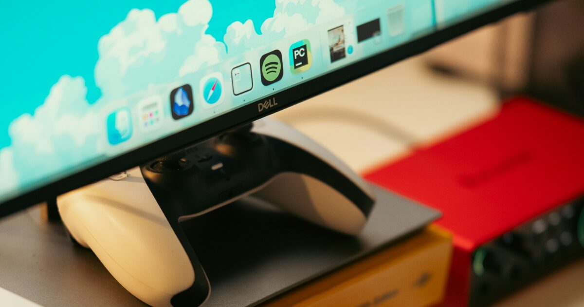 Dellモニターの下にコントローラーが置かれたカラフルなデスク環境