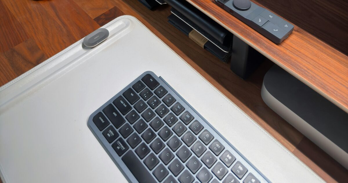 木製デスクの上に置かれたコンパクトなワイヤレスキーボードとリモコン